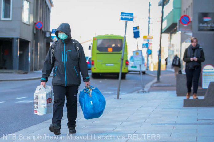 A man wearing a protective mask carries shopping bags as he walks on the streets of Oslo following an outbreak of the coronavirus disease (COVID-19)